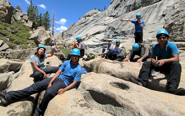 a group of backpacking students rest on rocks on an expedition with outward bound